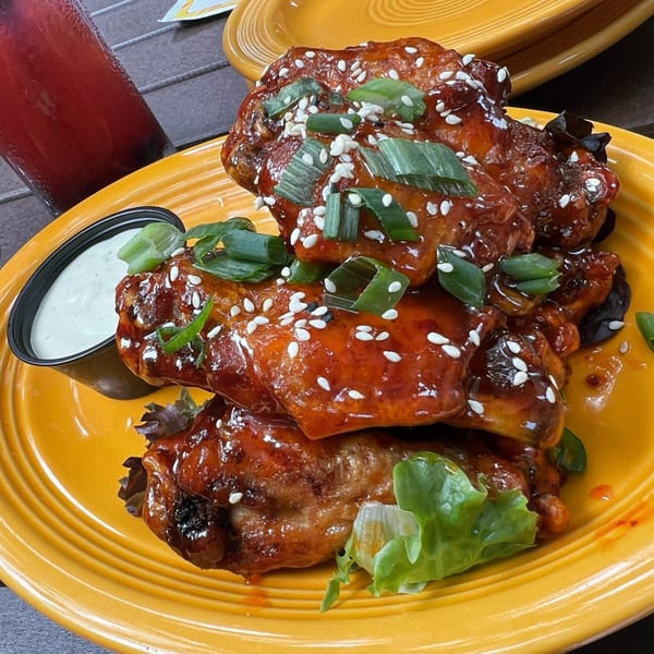 Glazed American chicken wings with sesame seeds and green onions, served with ranch dressing.