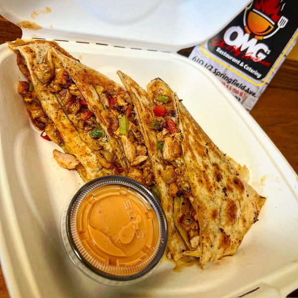 Oh My Goodness chicken quesadillas with peppers and onions, served with a side of sauce.