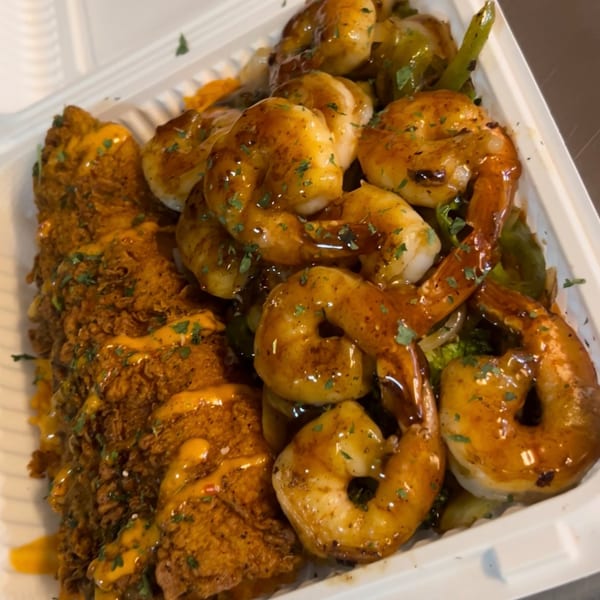 Crispy fried chicken and glazed shrimp with green peppers and onions in a white takeout container.